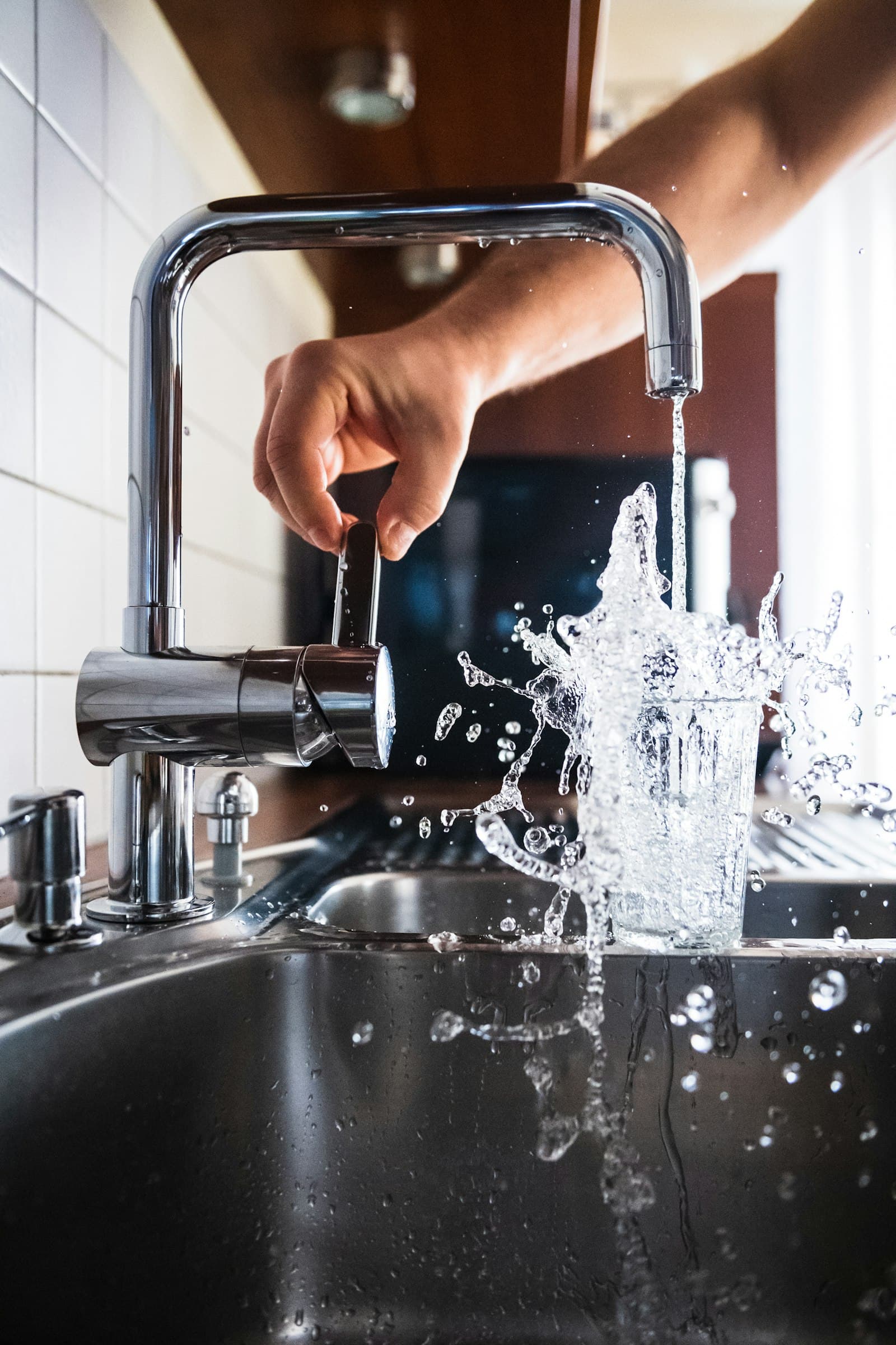 Hand aan een keukenkraan met stromend water